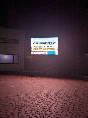 TINQ Opening celebration from December 8, 2025, through December 14, 2025. Crazy Discount => movable LED panel in front of the unfinished entryway to the Tesla Superchargers